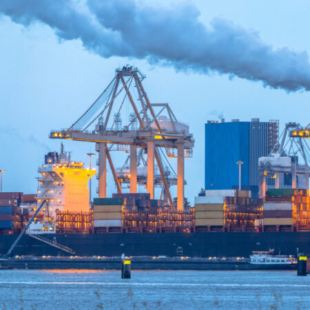 Container ships loading at Europoort tweede maasvlakte harbor in port of Rotterdam Netherlands at dusk during blue hour
